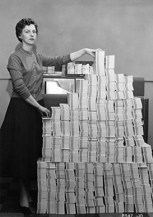 Programmer standing beside punched cards